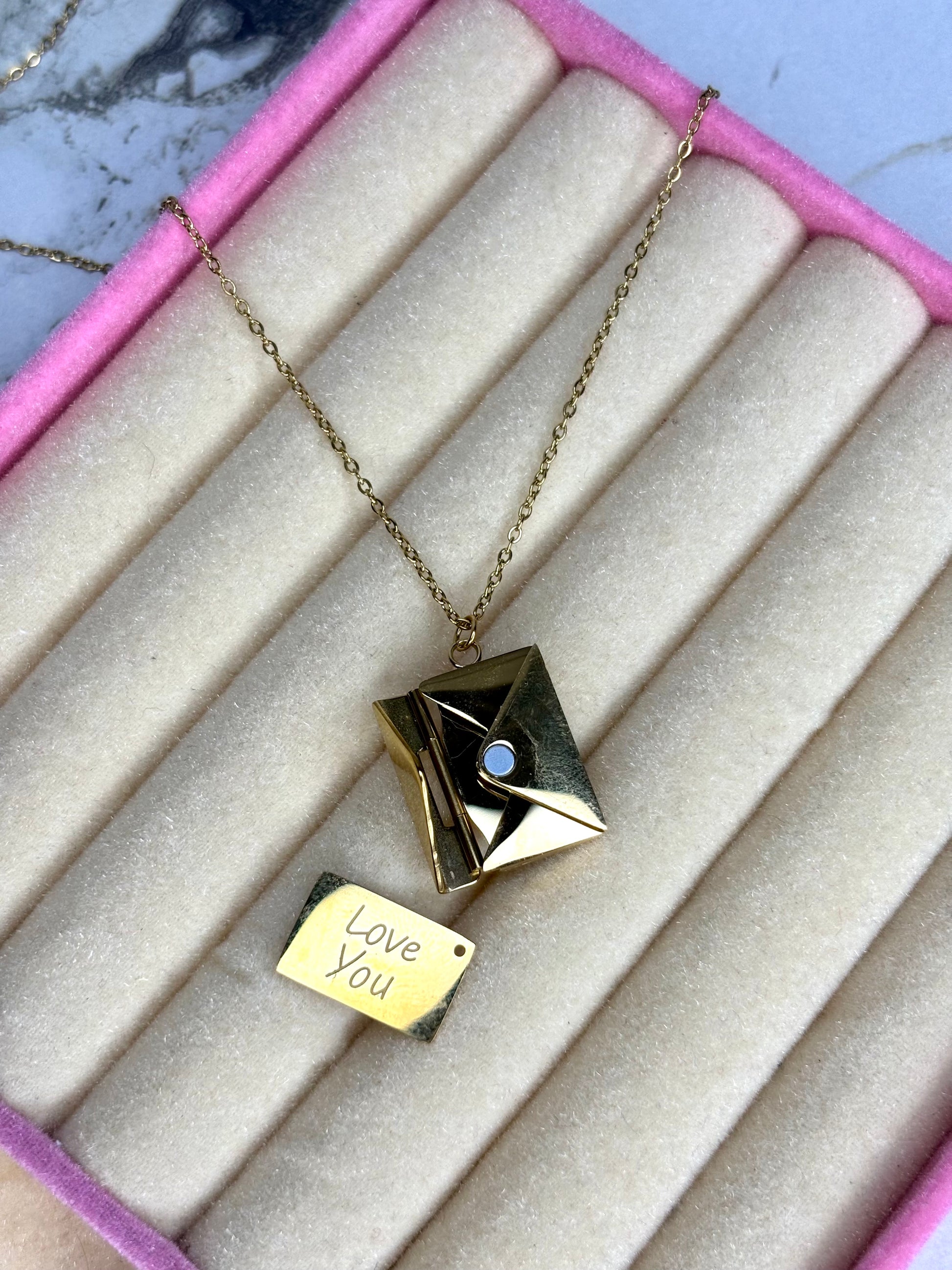 Necklace with a book-shaped pendant and 'Love You' tag on a textured surface